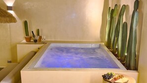 Ein Wellnessbereich mit Whirlpool, Kakteen und einer Obstplatte.