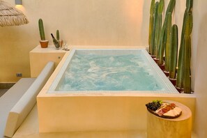 A hot tub with a cactus wall, a small table with a drink and glasses, and a fruit platter. - Tulum Experience Penthouse Downtown Pool View (Santo Domingo)