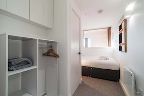 Een slaapkamer met een bed, een kledingkast, een hangrek en een radiator.