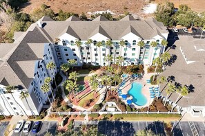An aerial view of a hotel with multiple floors, a swimming pool, and a parking lot. - Pool View Disney Universal Free Shuttle Parking (Orlando)