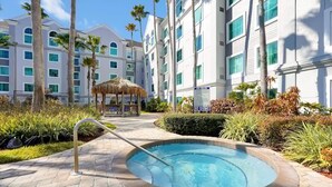 Un hotel con piscina, palmeras y una estructura de techo de paja.