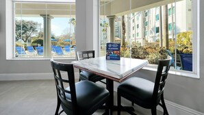 Habitación de hotel con un ventanal grande, una mesa de mármol y cuatro sillas negras.