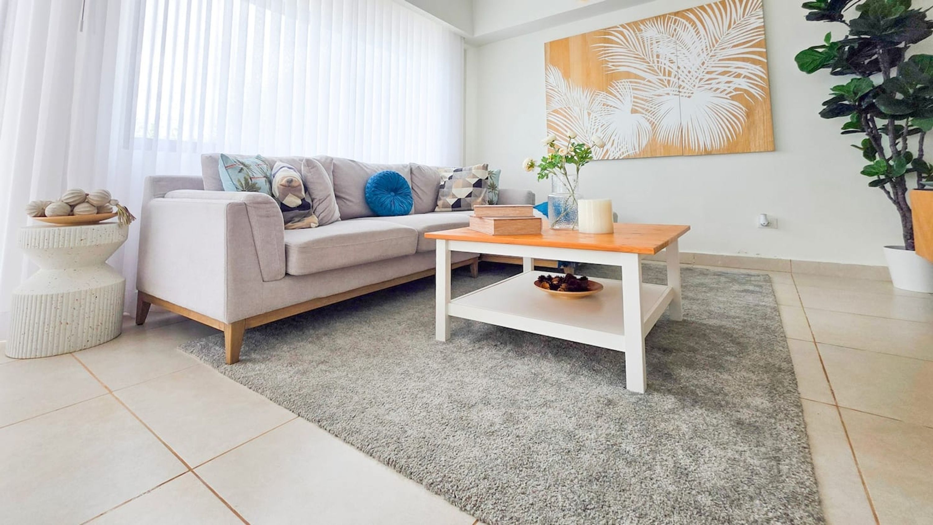 A modern living room with a sofa, a coffee table, a rug, and a wall art piece.