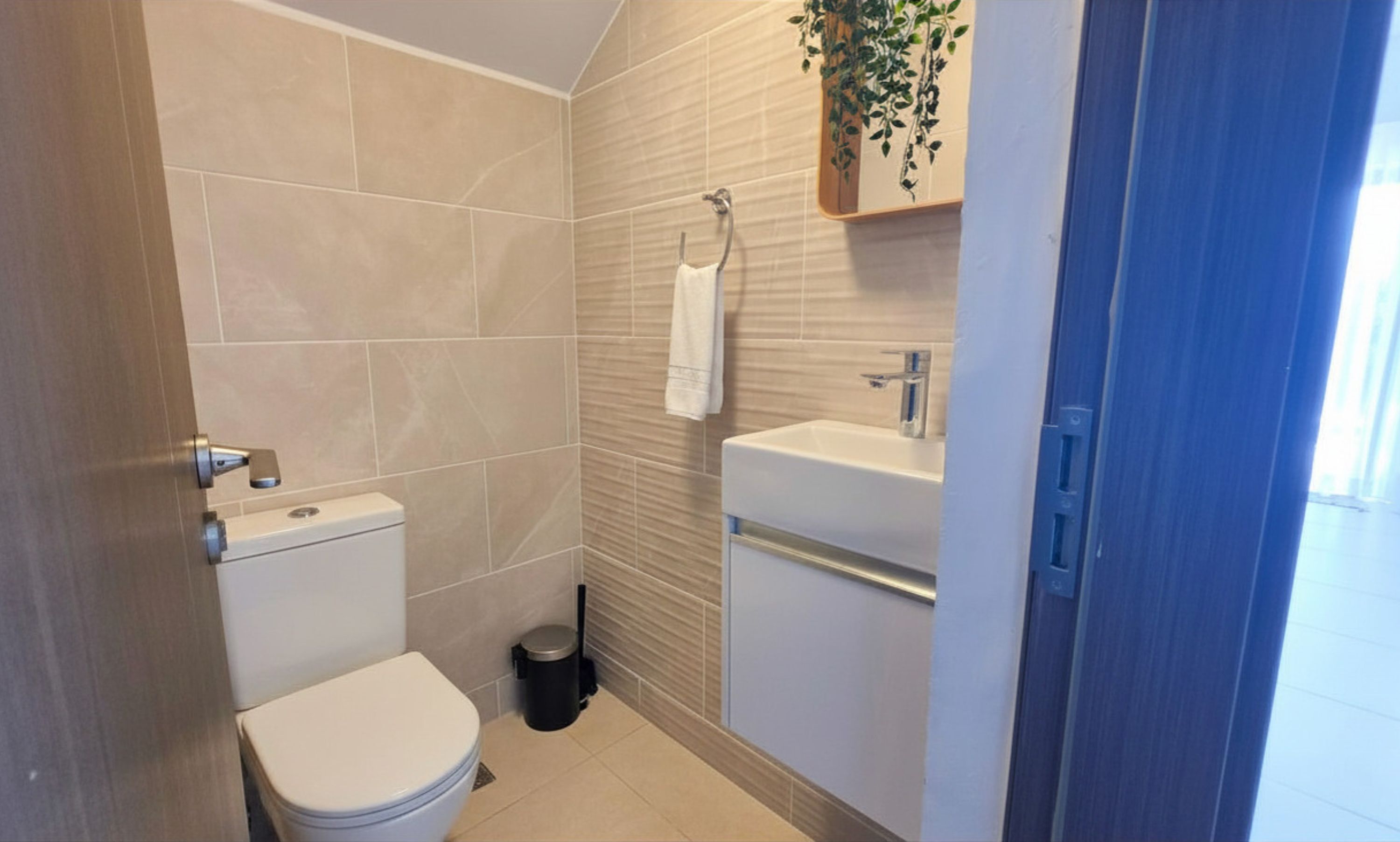 Een badkamer met een toilet, wastafel en een prullenbak.