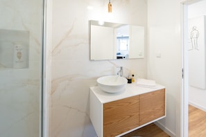 Une salle de bain moderne avec un lavabo blanc, un meuble-lavabo en bois et un grand miroir.