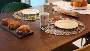 Ein Esstisch mit Gebäck, einer Obstkomposition und einem weißen Teller.