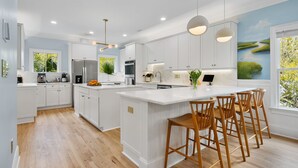 A modern kitchen with white cabinetry, a central island with bar stools, and recessed lighting.