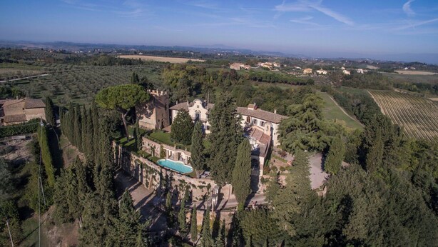 Une vue aérienne d’un vaste domaine comprenant plusieurs bâtiments, une piscine et de vastes espaces verts.