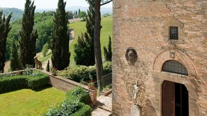 Un bâtiment en briques, avec un grand arbre, une statue et un jardin bien entretenu.