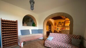 Um ambiente acolhedor com sofá, um banco e espaço para vinhos.