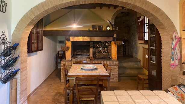 Uma sala de jantar com lareira de tijolos, mesa de madeira e cadeiras.