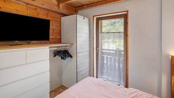 Ein Schlafzimmer mit Bett, Fernseher, Kleiderschrank und Fenster.