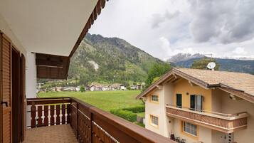 Ein Balkon mit Bergblick, ein Haus mit Satellitenschüssel und ein klarer Himmel.