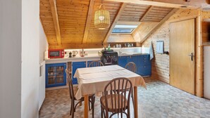 Une cuisine avec un plafond en bois, une table avec des chaises et un buffet bleu.