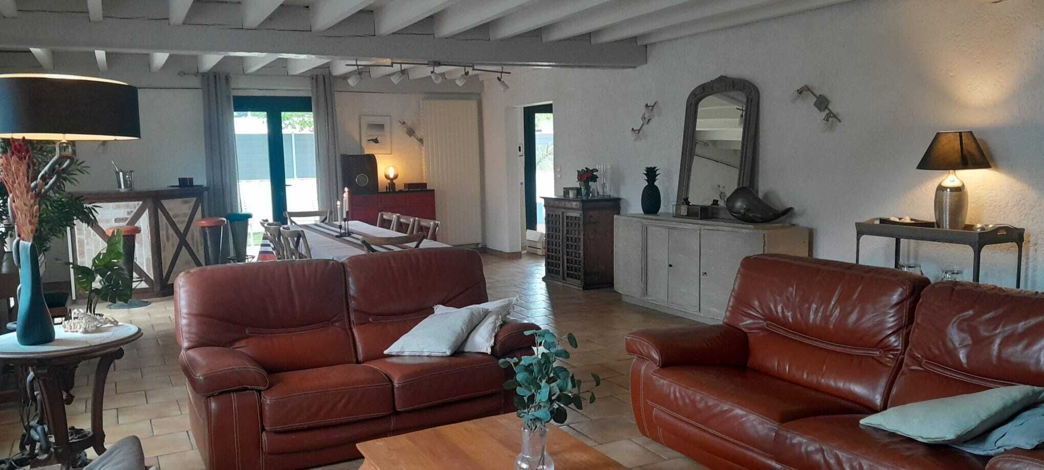 A spacious living room with leather sofas, a dining area, and a kitchen.