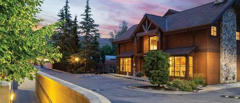 A large, multi-story lodge with a stone facade, large windows, and a well-lit entrance.