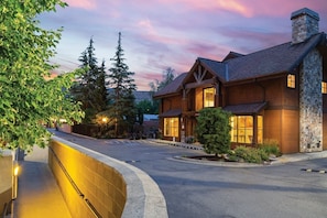 A large, multi-story lodge with a stone facade, large windows, and a well-lit entrance.