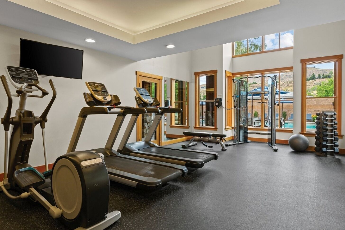 A gym with treadmills, elliptical machines, a bench, and a squat rack.