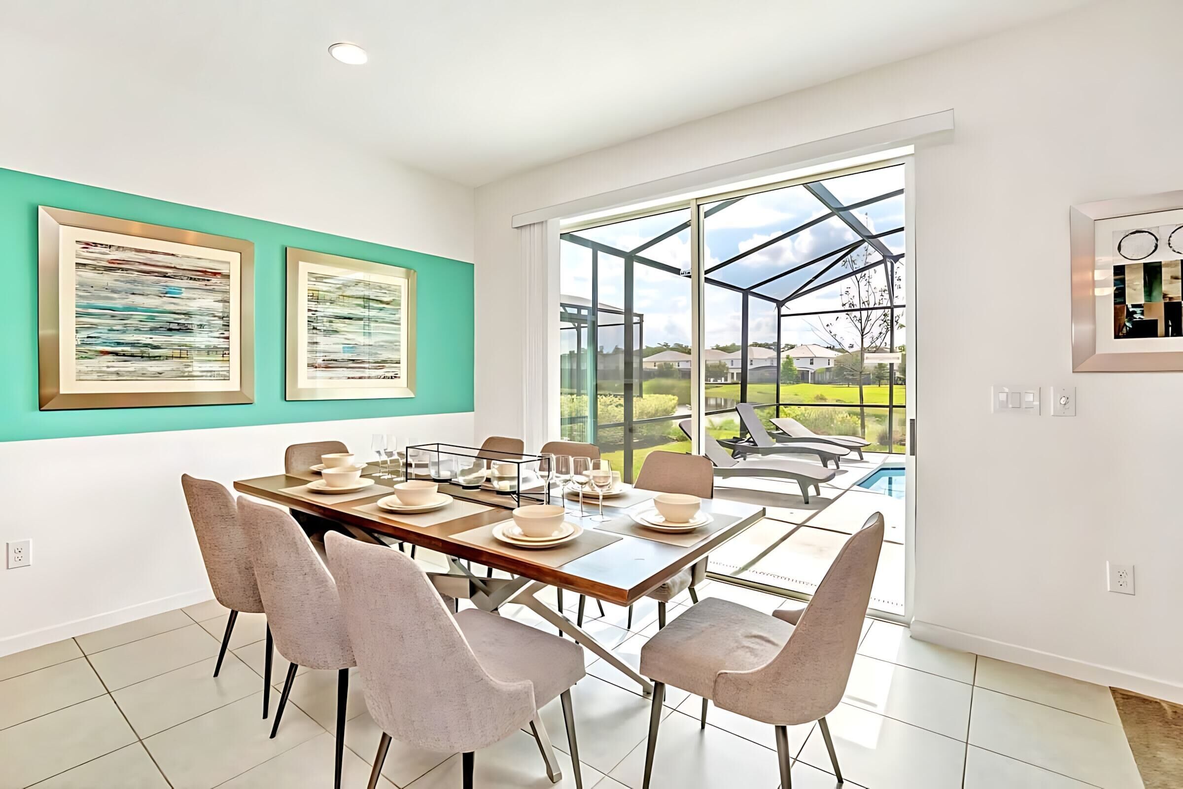 A modern dining area with a large table set for six, surrounded by chairs, and a glass enclosure leading to a pool.