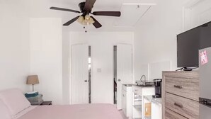 A bedroom with a bed, a ceiling fan, a TV, a dresser, and a wardrobe. - Room-private Studio Apartment in Vero Be (Vero Beach)