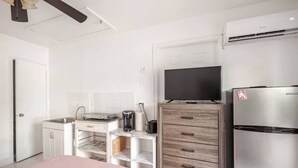 A compact kitchen with a refrigerator, a coffee maker, and a television on a wooden cabinet. - Room-private Studio Apartment in Vero Be (Vero Beach)