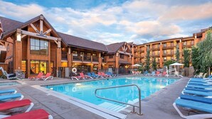 A hotel with a swimming pool, lounge chairs, and a building with a wooden facade. - Lake Ozarks | Family Lake Retreat | Pool + Lake | 3BR Sleeps 8 (Chelan)