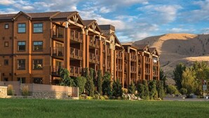 A multi-story hotel with balconies, a stone facade, and a mountainous backdrop. - Lake Ozarks | Family Lake Retreat | Pool + Lake | 3BR Sleeps 8 (Chelan)