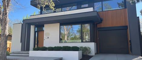 A modern two-story house with a garage, large windows, and a well-maintained front yard.