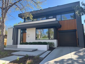 Una casa moderna a due piani con garage, ampie finestre e un giardino anteriore curato.