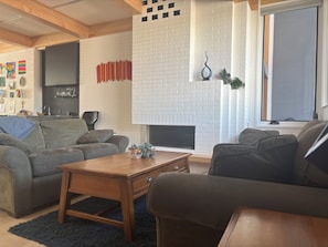 A living room with a fireplace, a sofa, a coffee table, and a TV. - Modern South Boulder 3BR Home Near Trails, Dining & Downtown (Boulder)