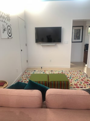 A living room with a flat-screen TV mounted on the wall, a colorful patterned rug, and a sofa with cushions. - Modern South Boulder 3BR Home Near Trails, Dining & Downtown (Boulder)