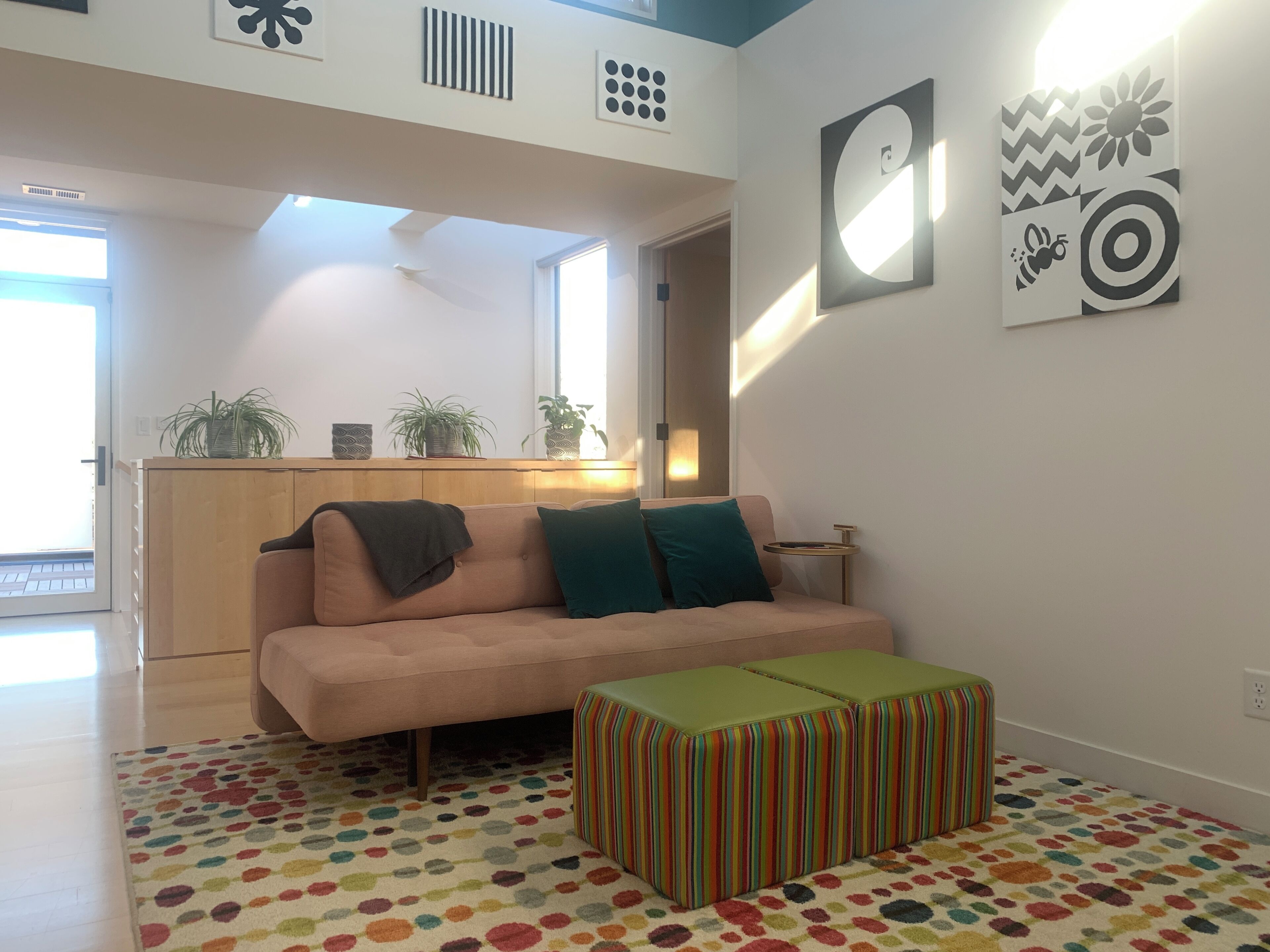 Una sala moderna con un sofá, una alfombra colorida y un reposapiés a rayas.