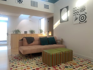 A modern living room with a sofa, colorful rug, and a striped ottoman. - Modern South Boulder 3BR Home Near Trails, Dining & Downtown (Boulder)