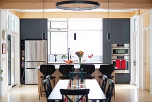 A modern kitchen with a dining area, large windows, and a central island. - Modern South Boulder 3BR Home Near Trails, Dining & Downtown (Boulder)