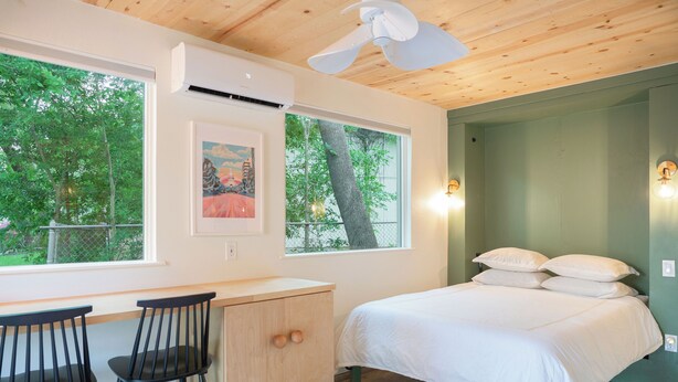 A bedroom with a bed, two chairs, a desk, and a window with a view of trees. - Designer E Austin Studio Close to Airport, Downtown, & UT Campus (Austin)