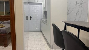 Eine moderne Küche mit Marmorarbeitsplatten, ein Essbereich mit Tisch und Stühlen sowie ein Schlafzimmer mit Bett und Vorhängen.