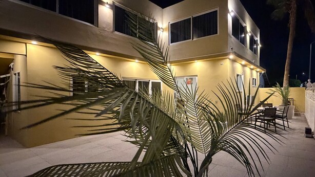Ein mehrstöckiges Gebäude mit flacher Fassade, zahlreichen Fenstern und einer Außenbereich-Sitzgelegenheit mit Tischen und Stühlen.