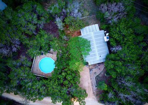 Ein Luftbild einer Anlage mit Schwimmbad, umzäunter Garten und einem Haus mit Metallbedachung.