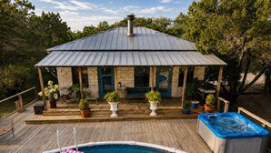 Ein Pool mit Whirlpool, eine überdachte Terrasse mit Sitzgelegenheit und Topfpflanzen.
