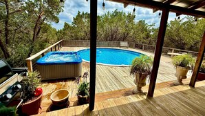 Eine Holzterrasse mit Whirlpool, Grill und Topfpflanzen.