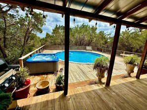 Eine Holzterrasse mit Whirlpool, Grill und Topfpflanzen.