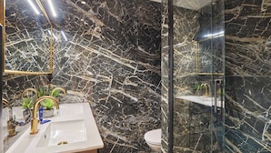 Une salle de bain avec un lavabo en marbre, des toilettes et une cabine de douche en verre.