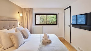 Une chambre d’hôtel avec un lit, une fenêtre donnant sur un paysage agréable, un téléviseur fixé au mur et une porte.