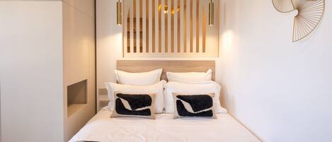 A modern bedroom with a bed, bedside lamps, a headboard, and a wall-mounted light fixture.