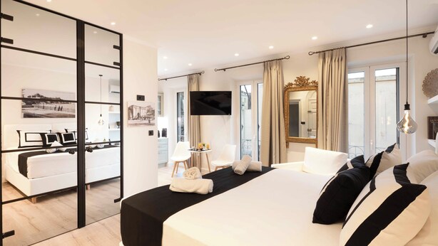 Ett modernt hotellrum med en stor säng, en TV, en spegel och utsikt över omgivningarna.