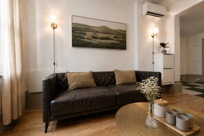 Un salon moderne avec un canapé en cuir, un tableau et un vase rempli de fleurs.