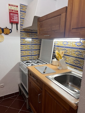 A kitchen with a gas stove, a sink, and wooden cabinets.