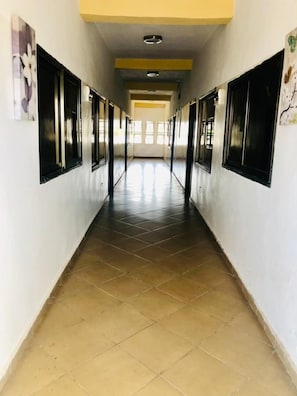 A corridor with tiled flooring, black-framed windows, and a yellow ceiling. - One Bedroom Apartment with Air Conditioning @ Royal Lanes Hotel, Achimota, Accra (Achimota, Accra.)