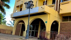Un hotel de varios pisos con fachada amarilla, balcones y una entrada central con toldo.