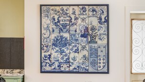 Een eettafel gedekt met borden, glazen en een taart, met een blauw-wit betegelde muur op de achtergrond.